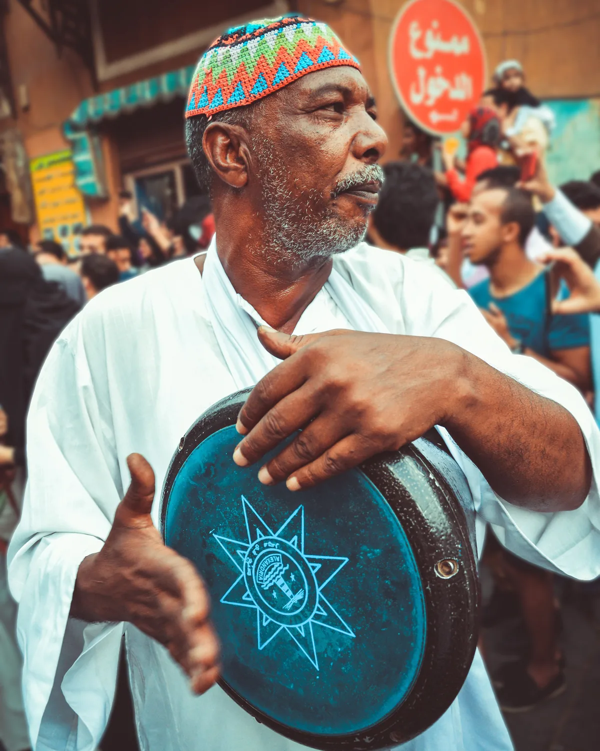 Un musicien en tenue traditionnelle jouant d'un tambour sur cadre lors d'une fête de rue au Moyen-Orient (photographie représentative, il ne s'agit pas de l'orchestre d'Al Hadheerah)